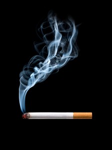 Closeup of cigarette on ashtray with wisp of smoke. Isolated